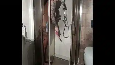 Busty woman takes a shower and masturbates with a dildo.